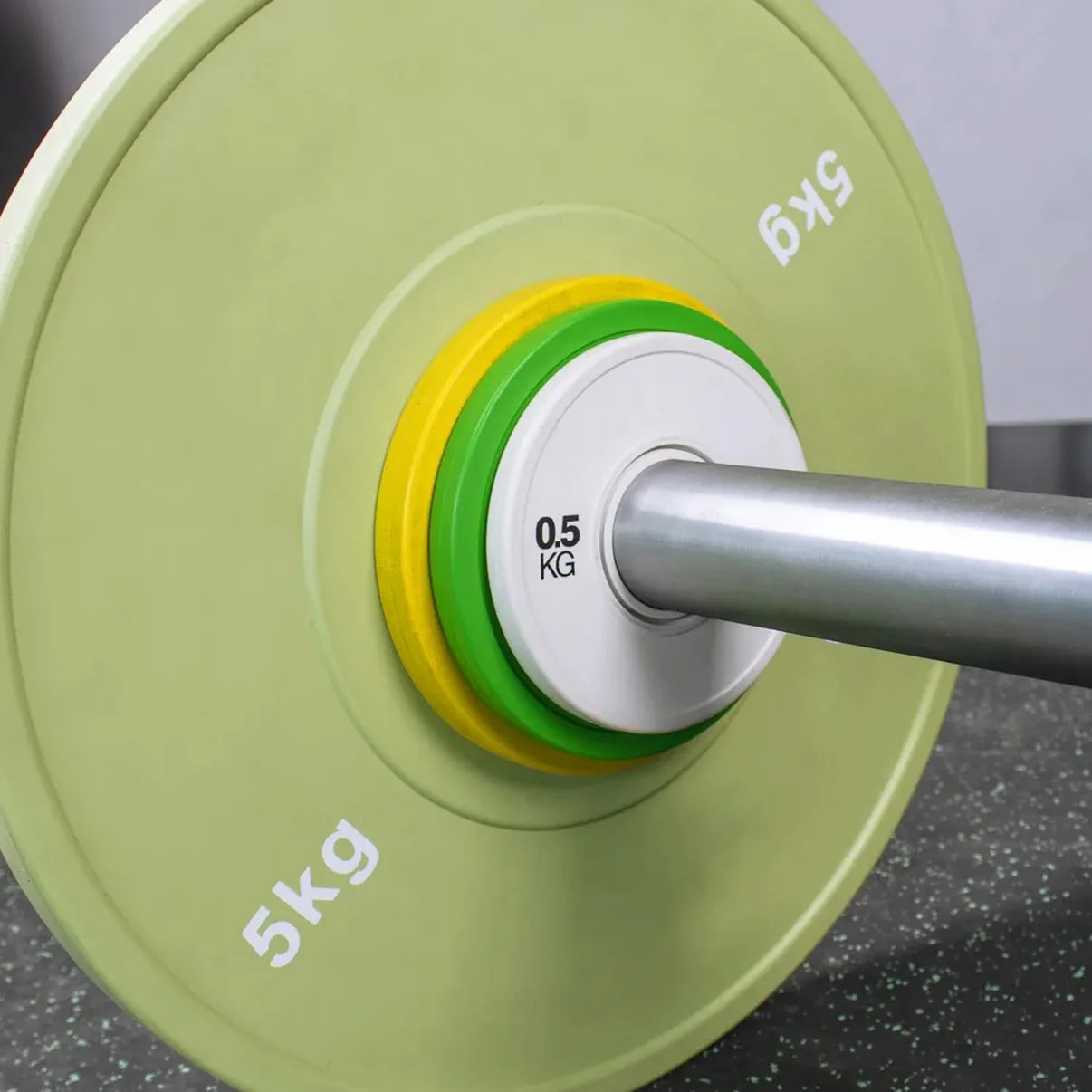 Close-up of a weightlifting bar with green weight plates on a dark surface